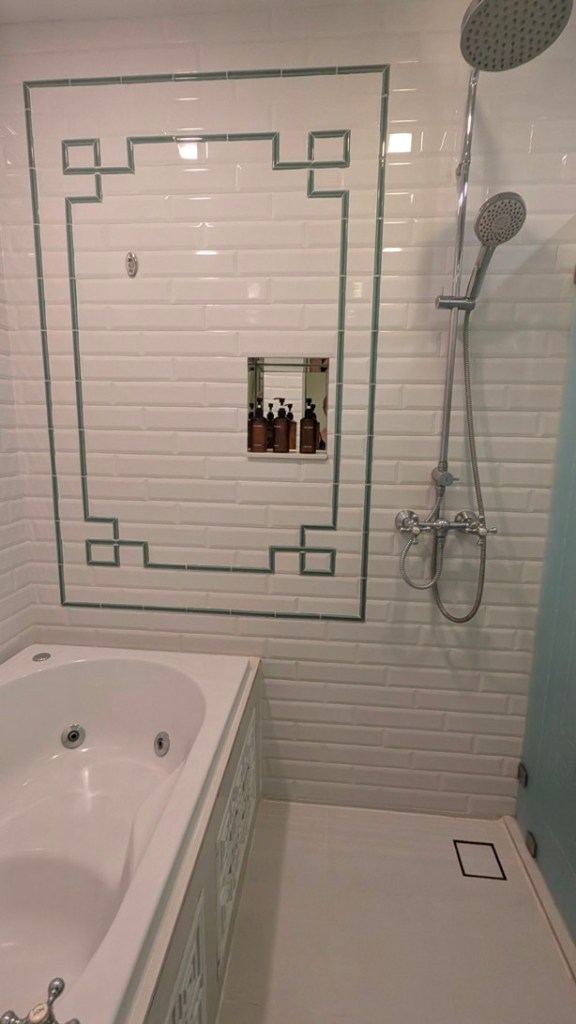 The Grand Deluxe Room at Riva Arun Bangkok provides a luxurious, pristine white-tiled bathroom with spa bath, shower and separate toilet.