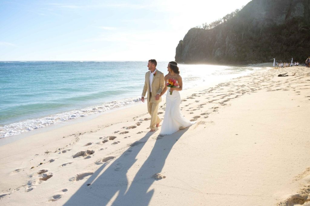 Blue-Lagoon-Cruises-Fiji-Weddings-bride-and-groom-walking-along-the-beach
